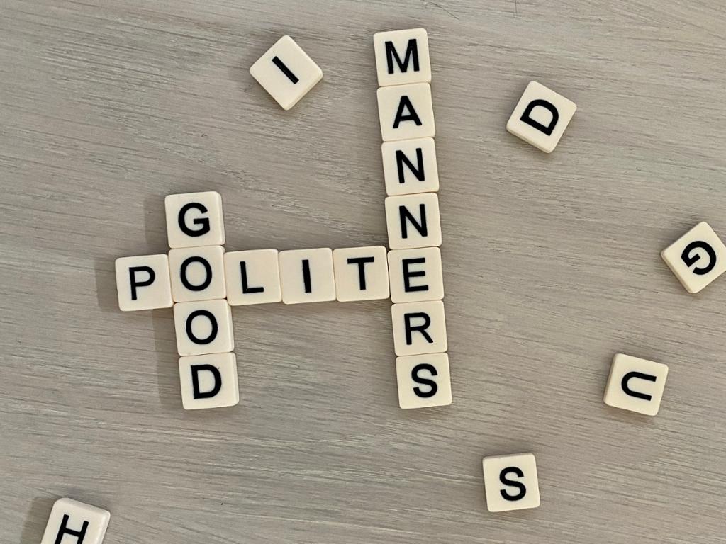Letter tiles spelling out the words polite, good, and manners. Photo.
