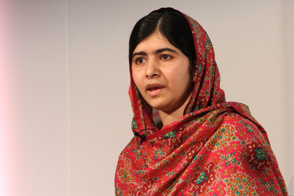 Malala Yousafzai dressed in a patterened, orange shawl. 