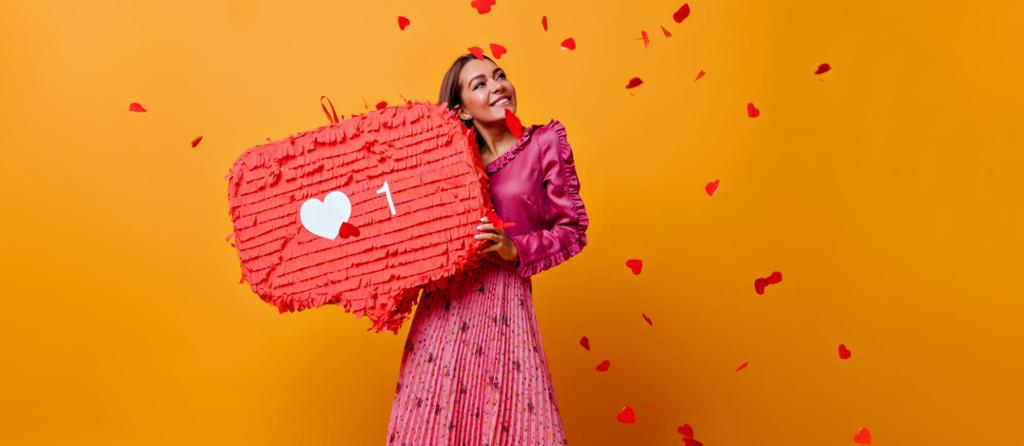 Jente med rosa kjole og hjerter som faller ned over henne. Hun holder en stor rød snakkeboble med et hjerte og tallet 1. Foto.