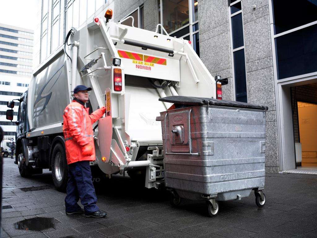 Bildet viser en renovatør som laster søppel i en renovasjonsbil.