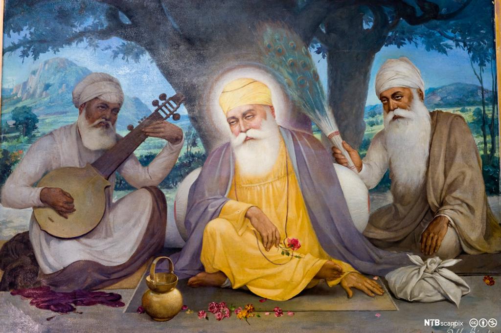 Mann i gul kjortel med turban sitter under et tre omgitt av to menn med hvit turban. Den ene spiller et instrument. Maleri.