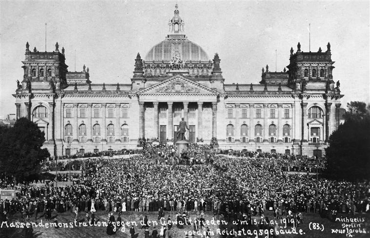 En stor folkemengde protesterer utenfor et stort praktbygg, riksdagsbygningen i Berlin. Foto.