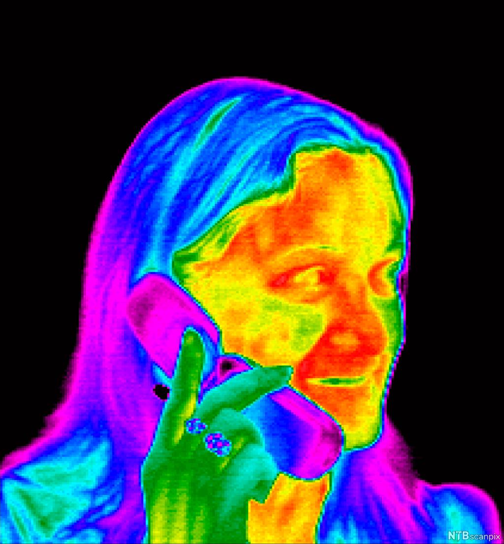 Bilde som viser ulike fargenyanser på de ulike temperaturene i motivet. Det er rødt og gult i ansiktet og halsen, blått og lilla på håret og mobiltelefonen og noe grønt på hånda og omriss i ansiktet. Infrarødt foto.