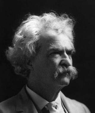 Photograph of Mark Twain.  He is an older man with bushy white hair, eyebrows, and moustache. 