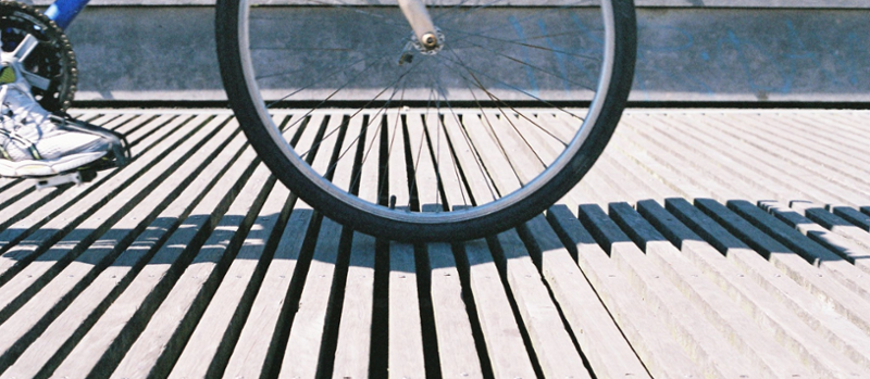 Syklist på et gulv av smale bjelker med spalter mellom. Foto.
