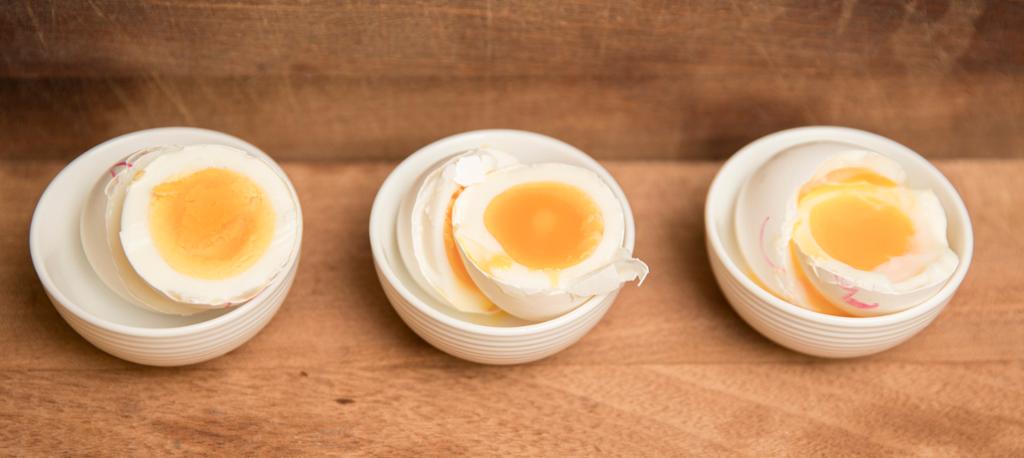 Tre egg i hver sin lille skål. Eggene er delt i to og viser ulik konsistens på plommene. Foto.