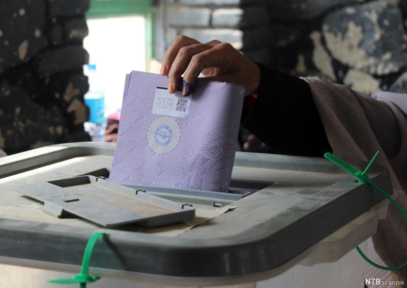 En mann legger en stemmeseddel i en stemmeurne i Afghanistan. Foto. 