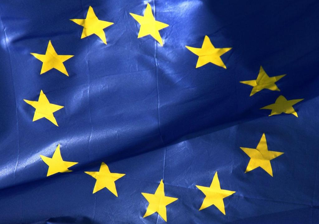 Foto av EU-flagget, med tolv gylne stjerner i sirkel på mørkblå bunn.