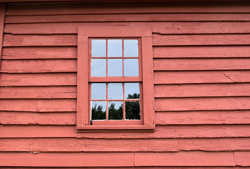 Rødmalt husvegg og vindu med gammel bordkledning. foto.