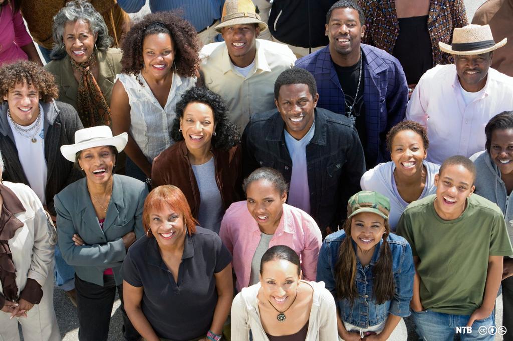 Photo: A group picture of several African Americans, taken from above. They are looking up at the camera, smiling.