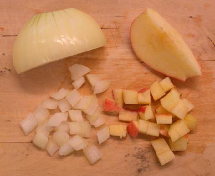 Små bitar av eple og lauk på ei skjerefjøl. Foto.