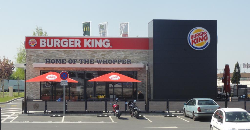Burger King-restaurant med motorsykler og biler parkert utenfor. Foto. 