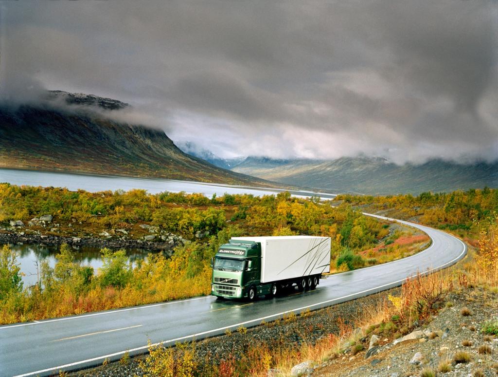 Foto av lastebil som er alene på veien i fjellandskap.