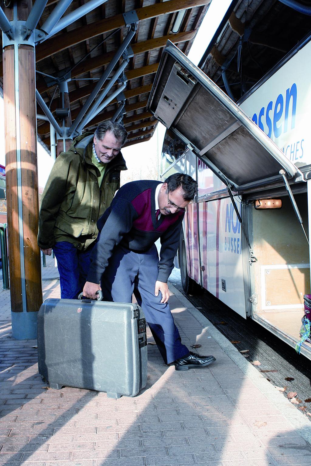 Bussjåfør hjelper til med å legge koffert i bagasjerom.foto.