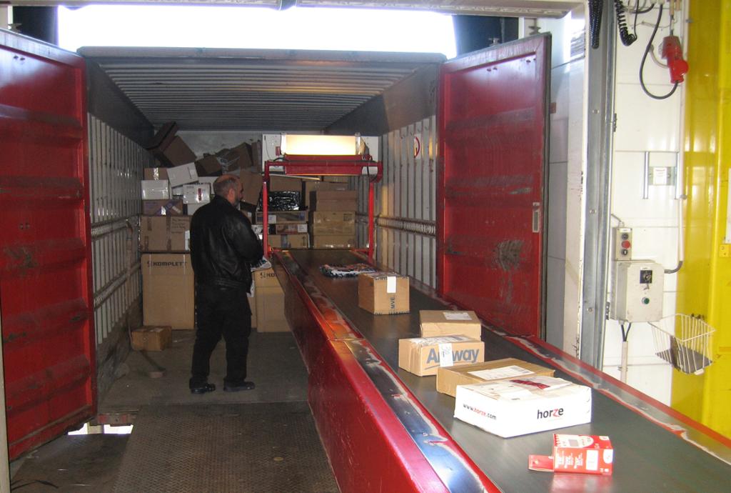 Stykkgods transporteres på samlebånd til kontainer. foto.