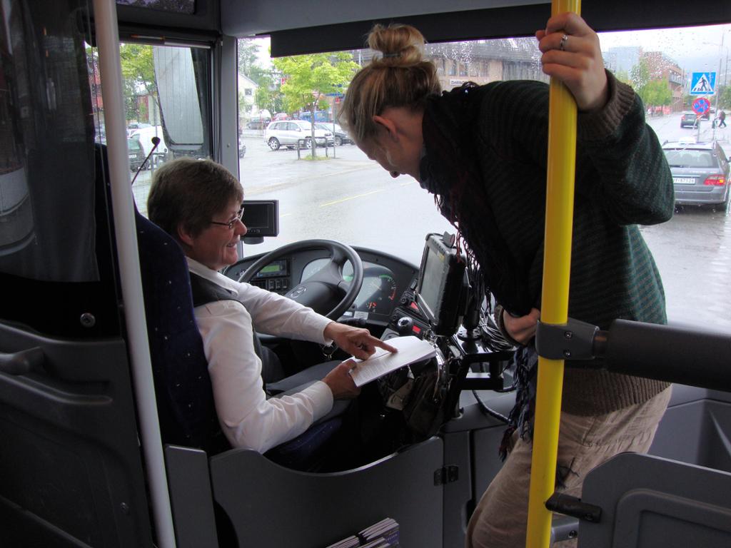 Bussjåfør og passasjer i samtale på bussen. foto.