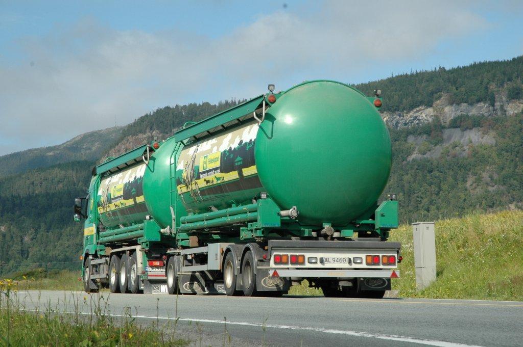 Grønn og gul bulkbil som transporterer to tanker med Felleskjøpets logo på. Foto.