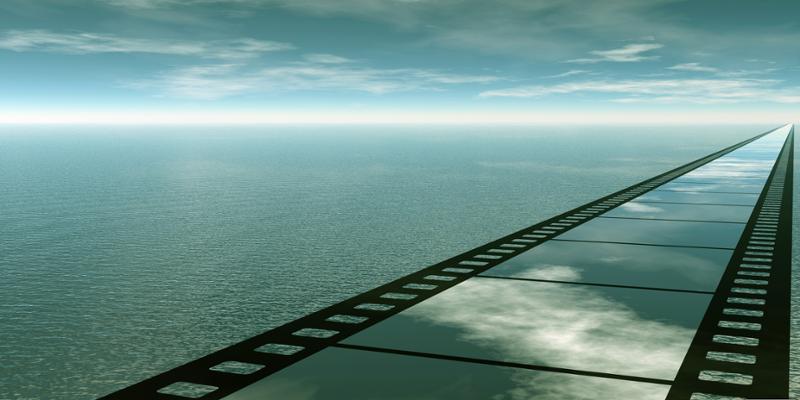En bro formet som en filmstripe krysser havet og strekker seg mot horisonten. Blå himmel og skyer speiler seg i broen/filmstripen. Manipulert foto.