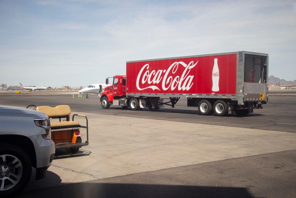 Lastebil med Coca-Cola-logo på en flyplass. Foto.
