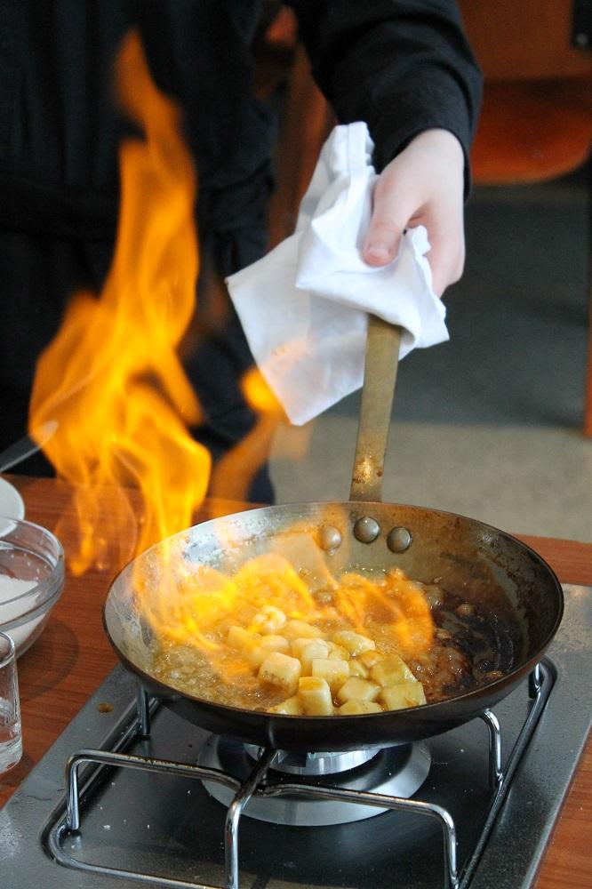 Bananar i terningar blir flamberte i ei steikjepanne. Foto.