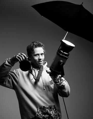 En fotograf holder opp et kamera og en lyskaster. Foto.