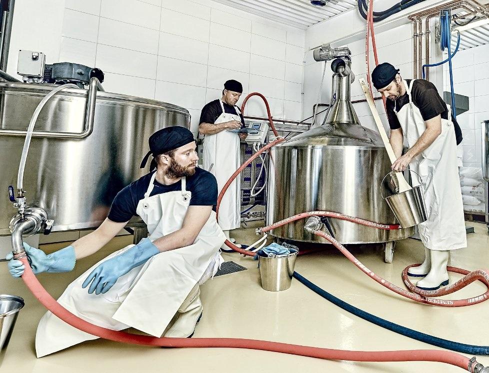 Tre personer er i gang med å brygge øl på et bryggeri. Foto.