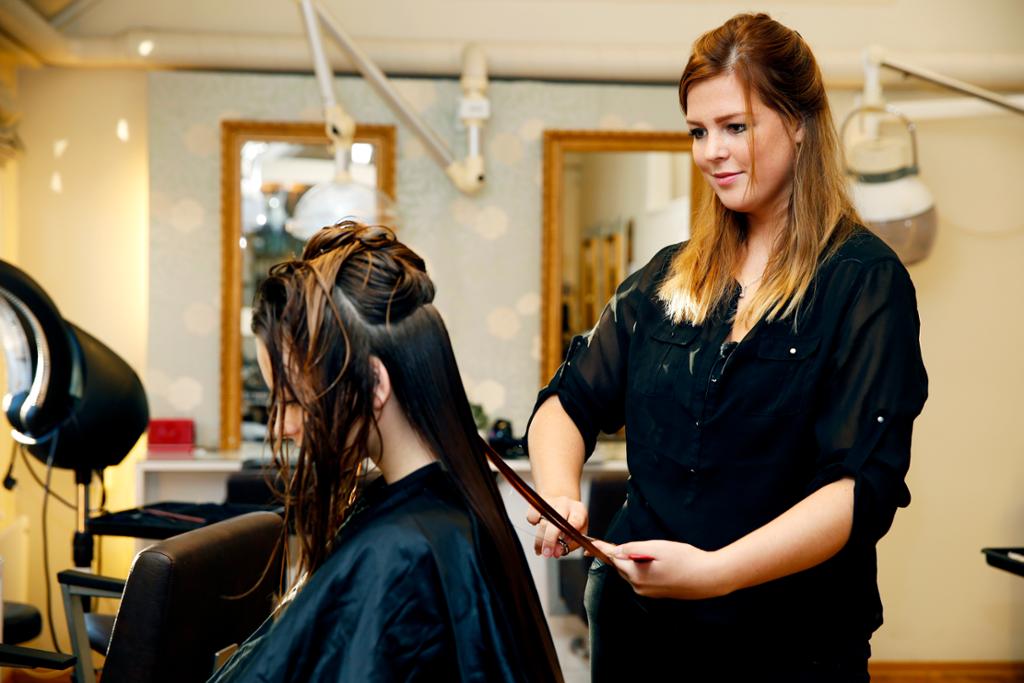 Frisørlærling jobber med håret til en kunde. Foto.