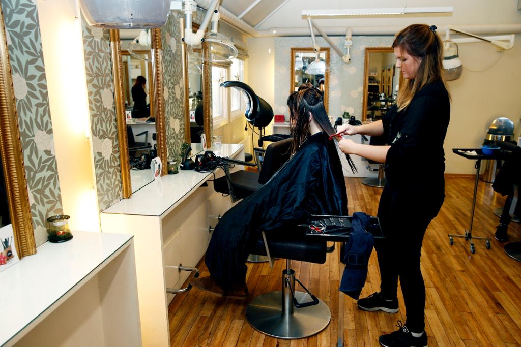 Frisørlærling klipper håret til ein kunde. Foto.