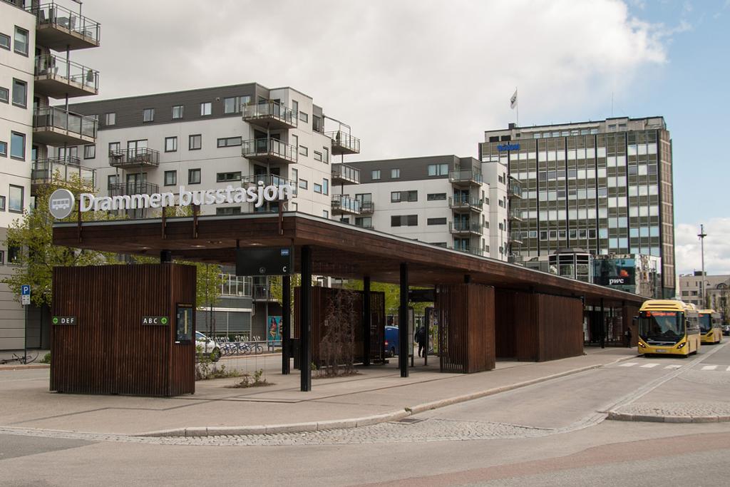 En busstasjon hvor det står to busser. Skilt viser plass A, B og C på den ene sida og D, E og F på den andre sida. Foto.