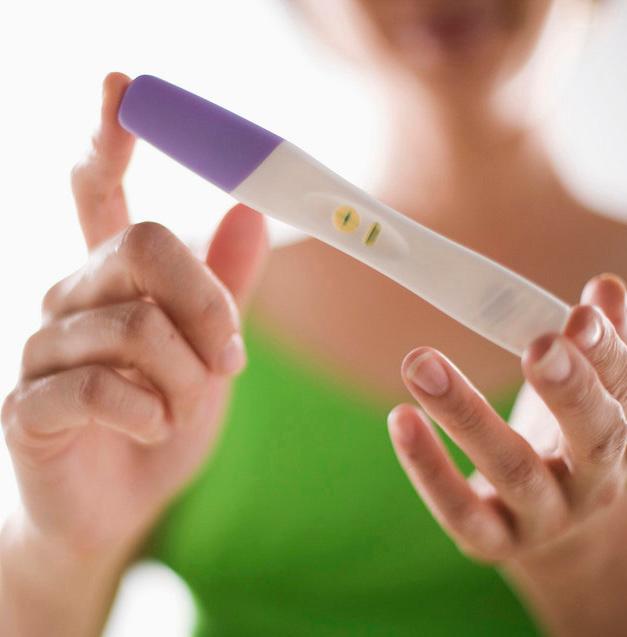 Kvinne holder opp en graviditetstest. Foto.
