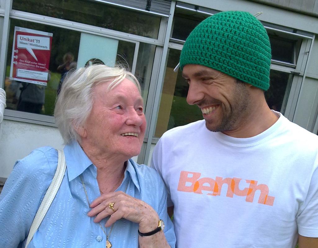 Eldre dame og ung mann som smiler til hverandre. Foto.