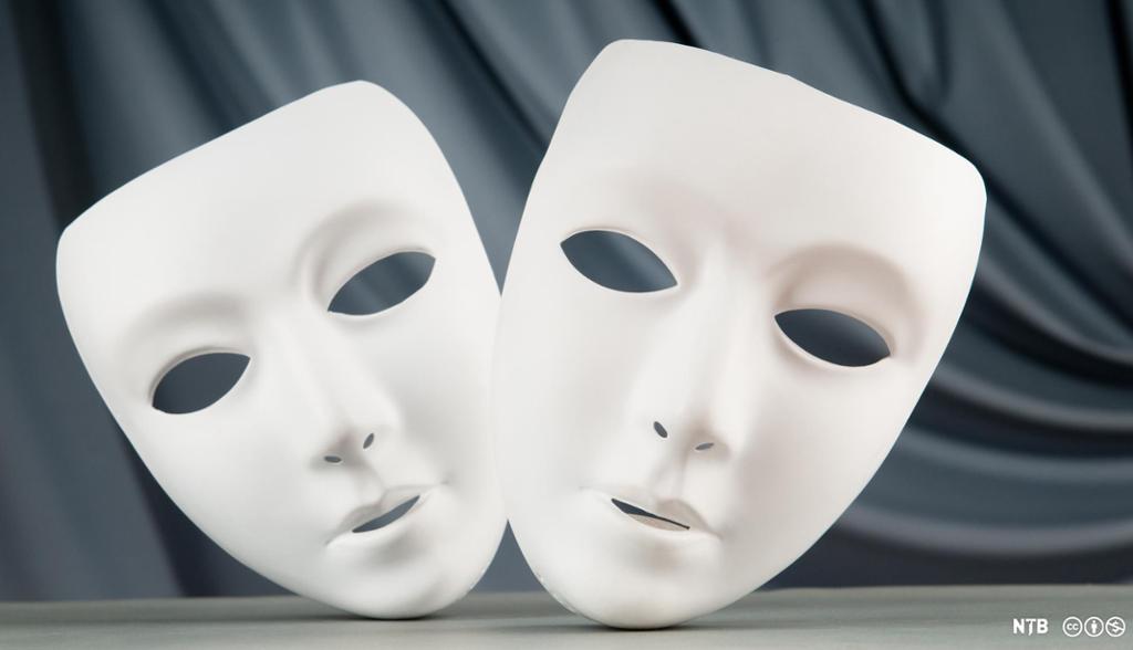 Theatre masks, two white masks with no expression, against a black background.  Photo.