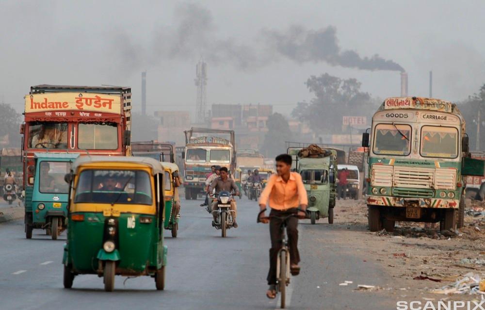 Gutt på sykkel i forurenset India. Foto.