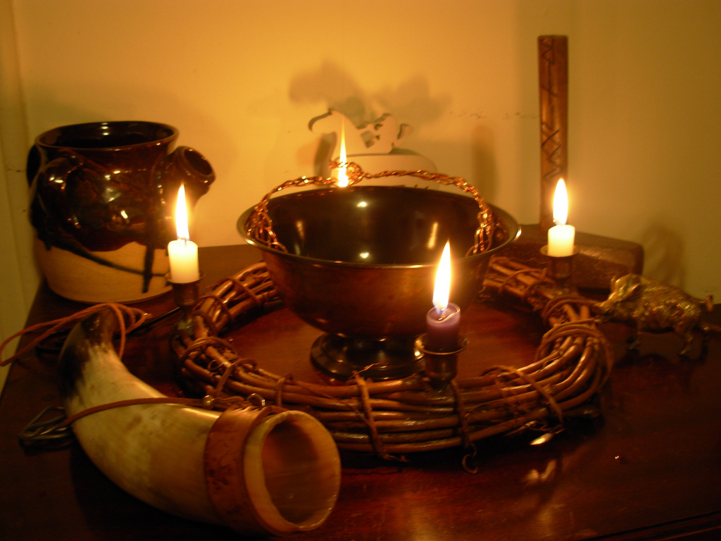 Altar med skål, drikkehorn, lyskrans, kanne og ein grisefigur. Foto.