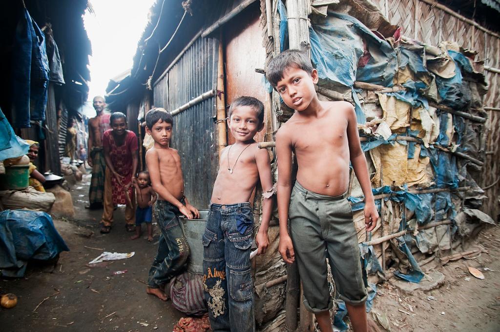 Family on a street corner in Bangladesh slum, woman with small child, man, three boys. 