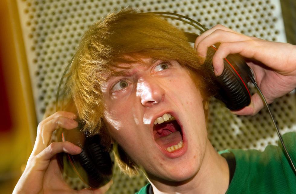 Gut som lyttar til høg musikk gjennom øyretelefonar. Foto.