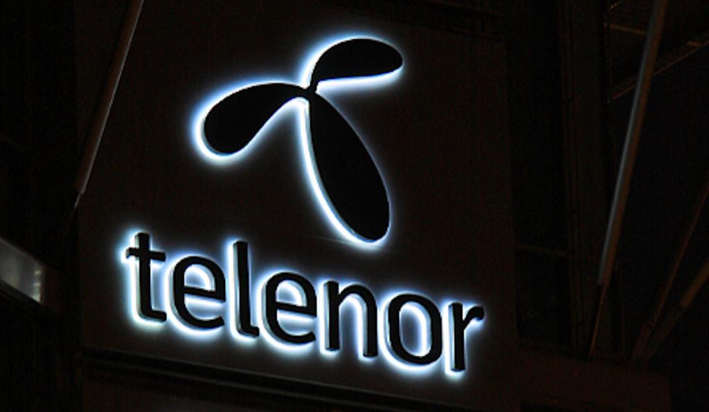 Fotografi av Telenor sin logo med lys i bakgrunnen.