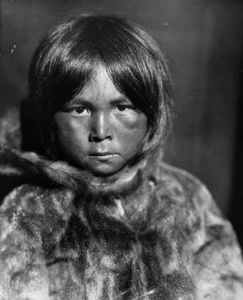 Portrett av et inuittbarn i pelsjakke. Svart-hvitt foto.