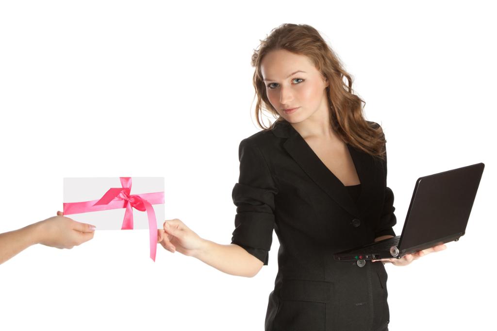 Forretningskvinne poserer med en laptop samtidig som hun tar imot en gave. Foto.