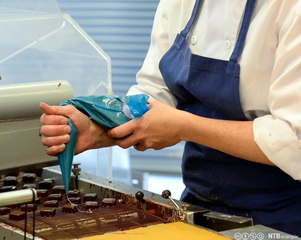 Konditor pynter konfektsjokolade. Bilde.