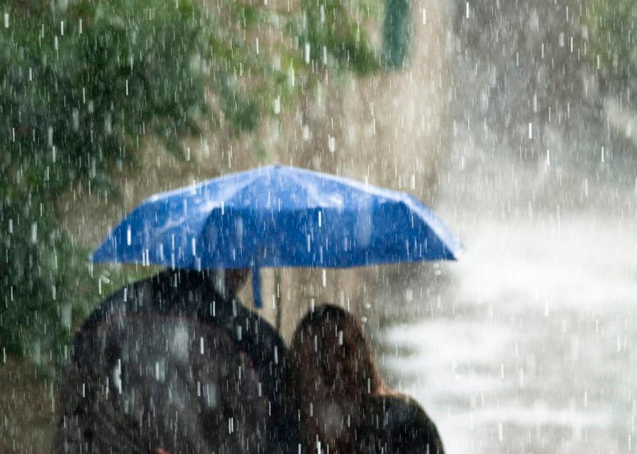To mennesker som søker ly under samme paraply under en kraftig regnbyge.
