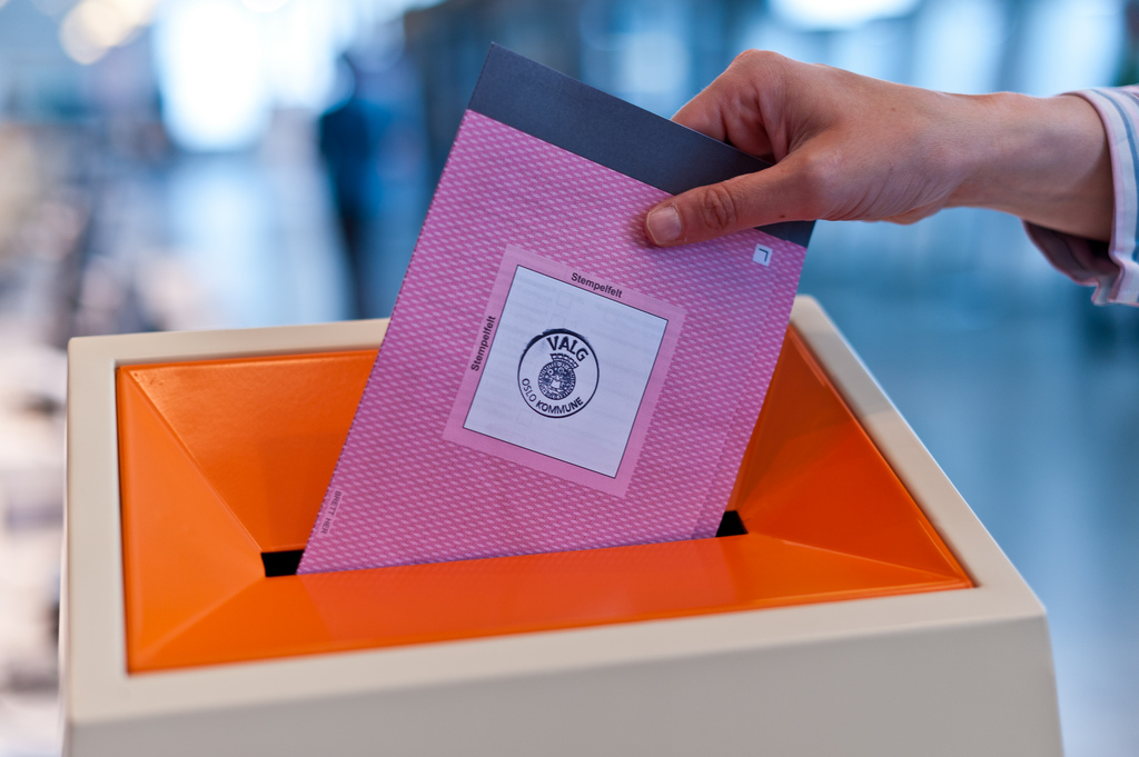 En person putter stemmeseddel i valgurne. Foto.