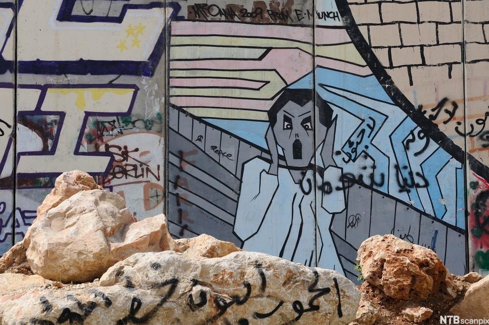 Bilde med Skrik-motiv malt på en mur med graffiti på. Muren har israelske myndigheter satt opp som et skille mellom israelere og palestinere på Vestbredden. Foto.
