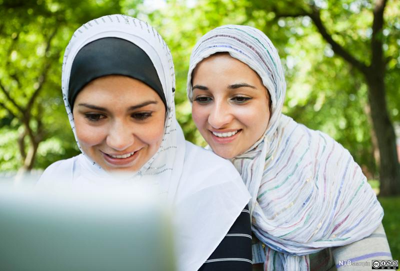 To unge jenter med hidjab ser på PC-skjermen. Foto.