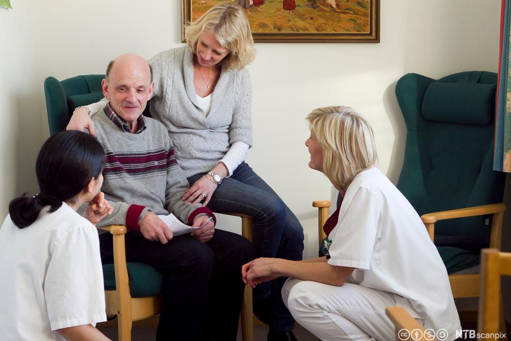 Pasient og pårørende i samtale med helsefagarbeidere. Foto.