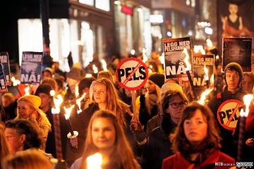 Mange personer som går i fakkeltog mot pels. Foto.