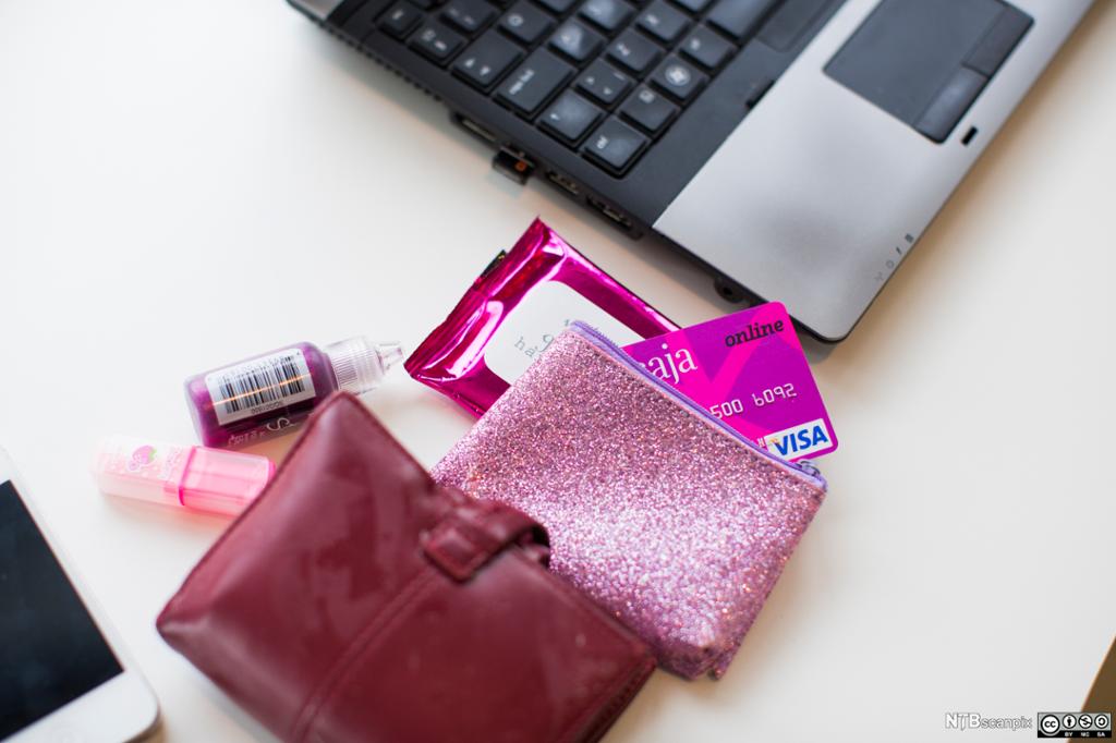 Lommebok med kredittkort ved siden av en pc. Foto. 