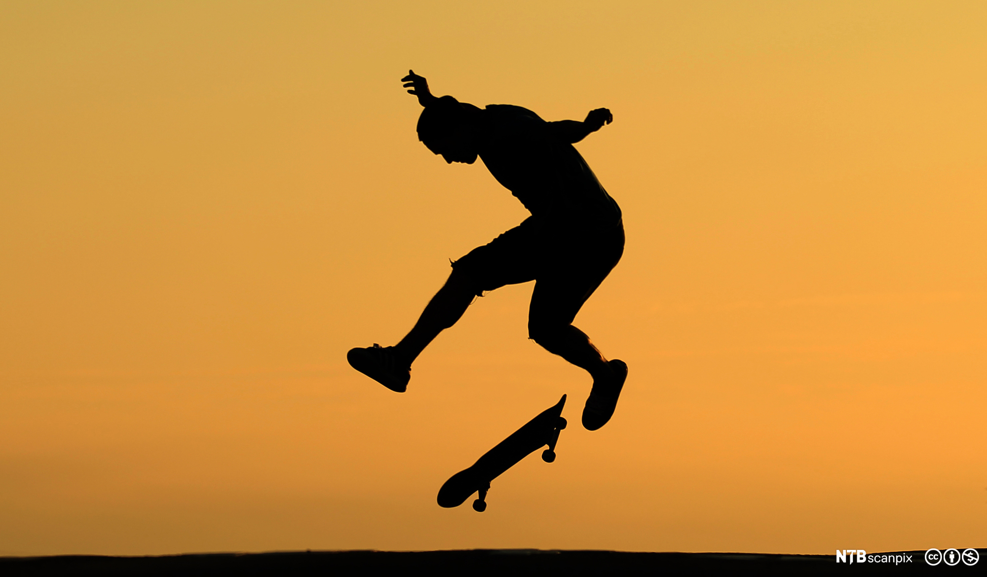 Ung mann gjer triks med eit skateboard. Foto.