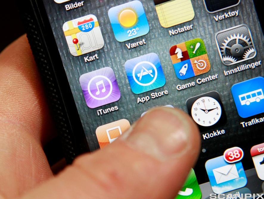 En person holder i en smarttelefon som viser apper. Foto.