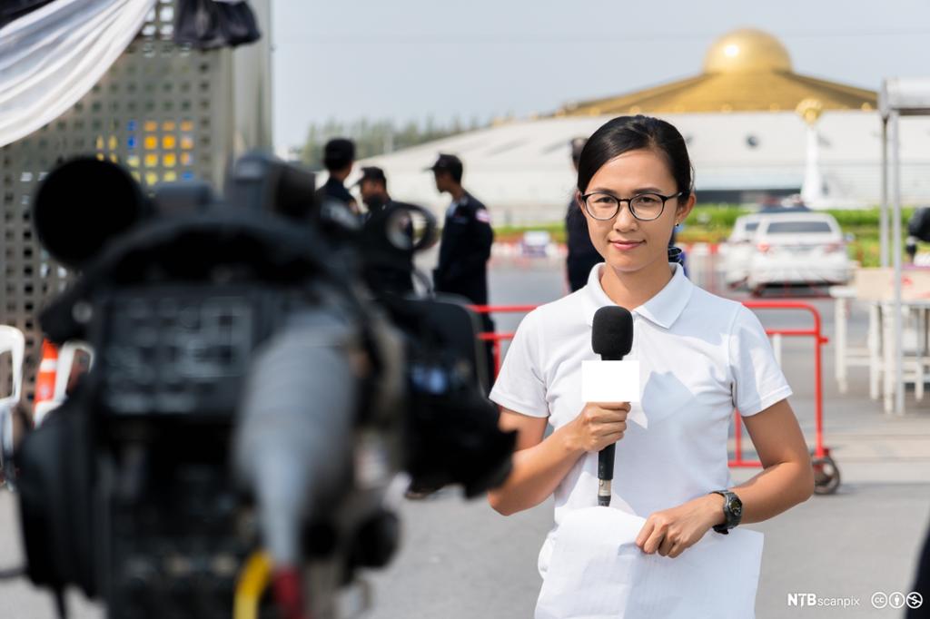 Kvinnelig reporter foran kamera. Foto.